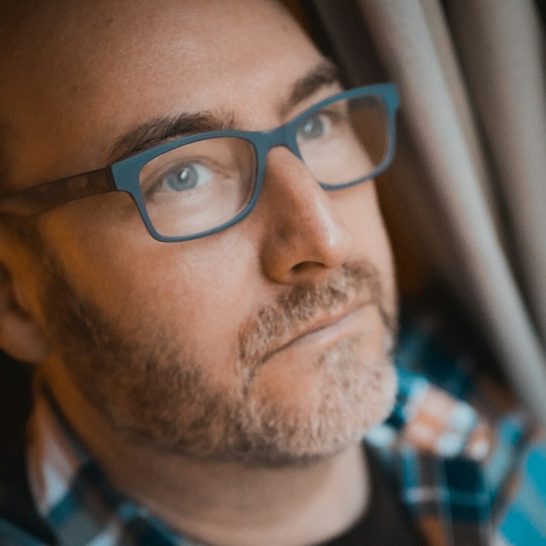 Professional headshot of a man with glasses in business attire